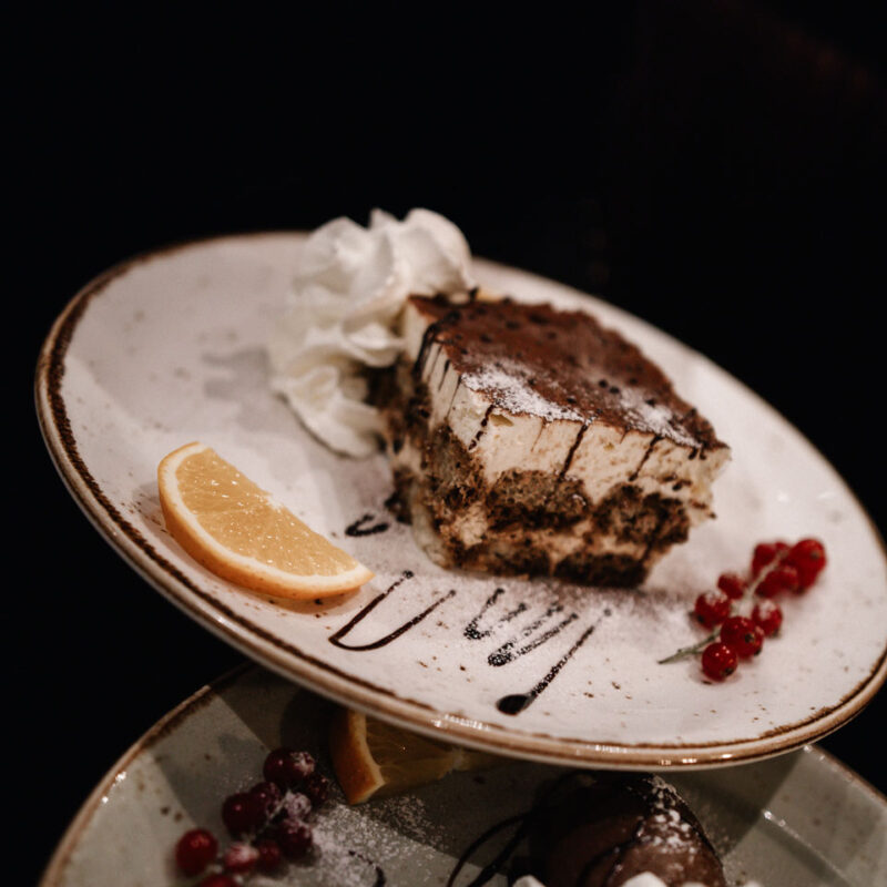 Dessertteller mit Tiramisu und Sahne dekoriert serviert