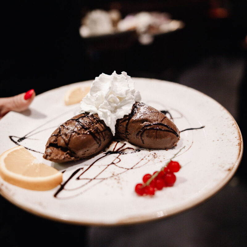 Dessertplatte mit Schokoladeneis und Sahnehäubchen serviert